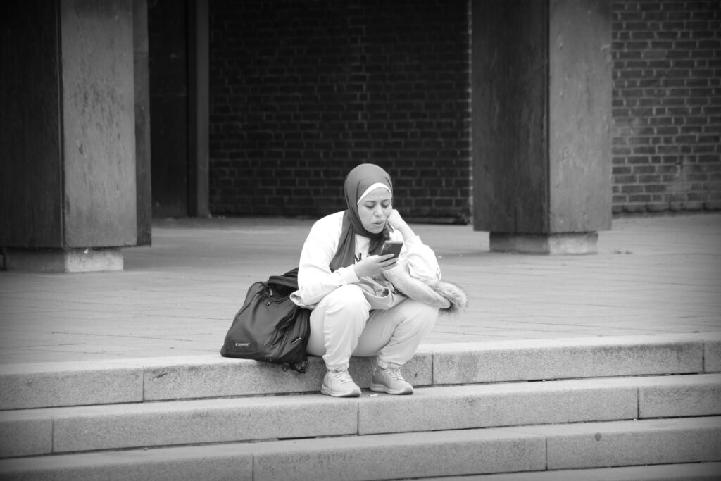 A lone Muslim woman sitting on the steps of the Bürgerschaft building, Marktplatz, Bremen