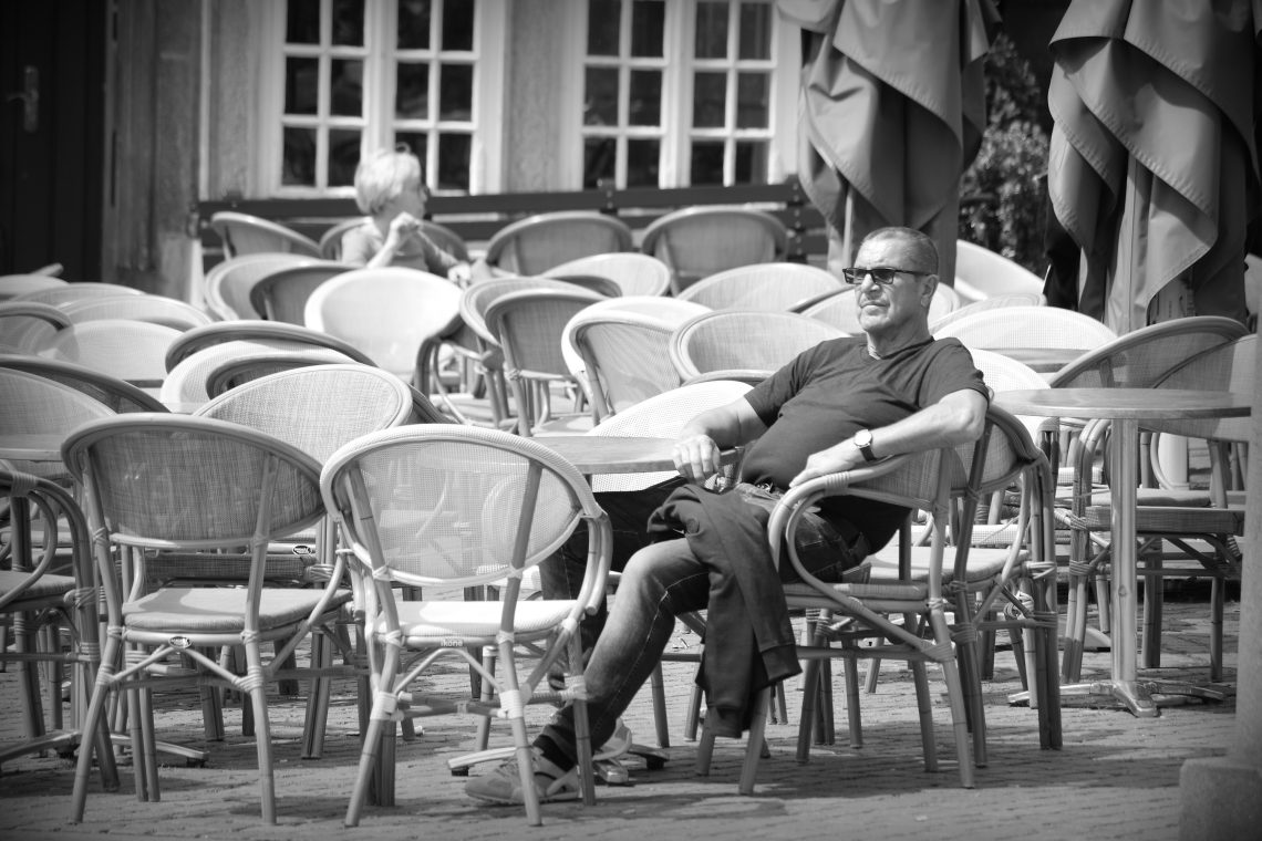 A man relaxes in the sun at a restaurant table on Domplatz, Bremen