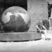 A lone man sitting in front of a massive stone globe, set up as a fountain, in Hamburg.
