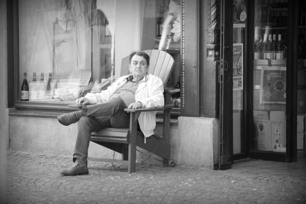 An older man relaxing in a chair outside a shop in Osnabrück.
