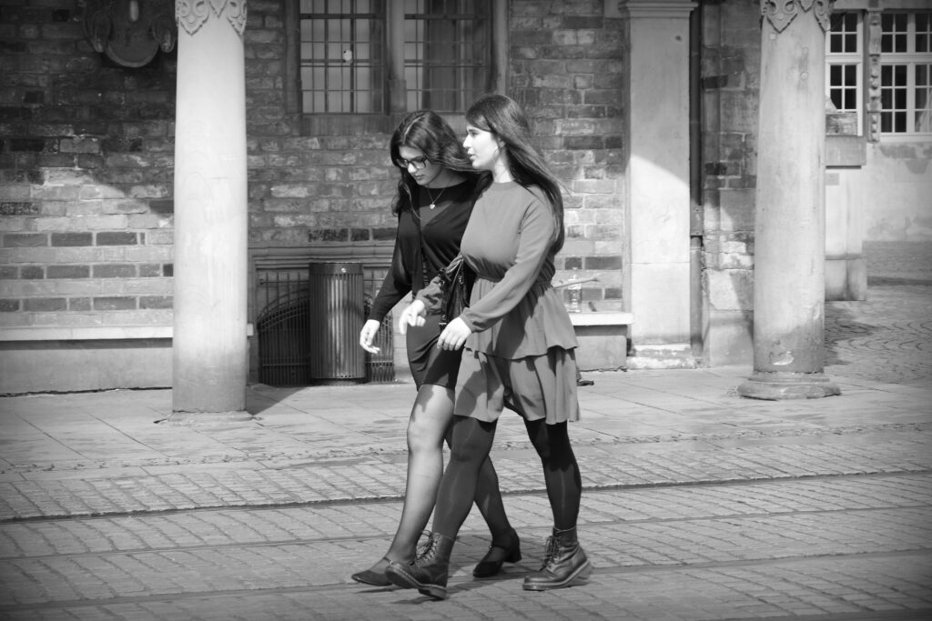 Two young women walking across the tram lines on front of the old Town Hall in Bremen.