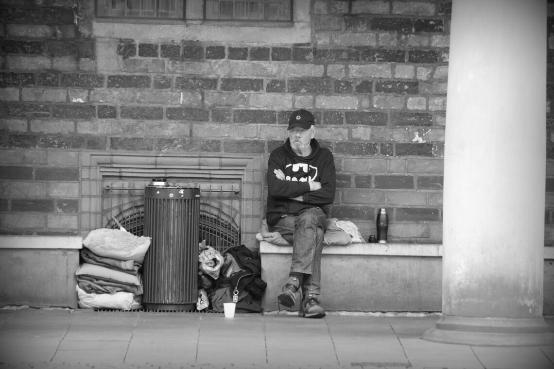 A man wearing a Batman shirt sitting next to his possessions in Bremen