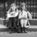 Two young women sitting together on the stone steps under the Roland statue in Bremen.