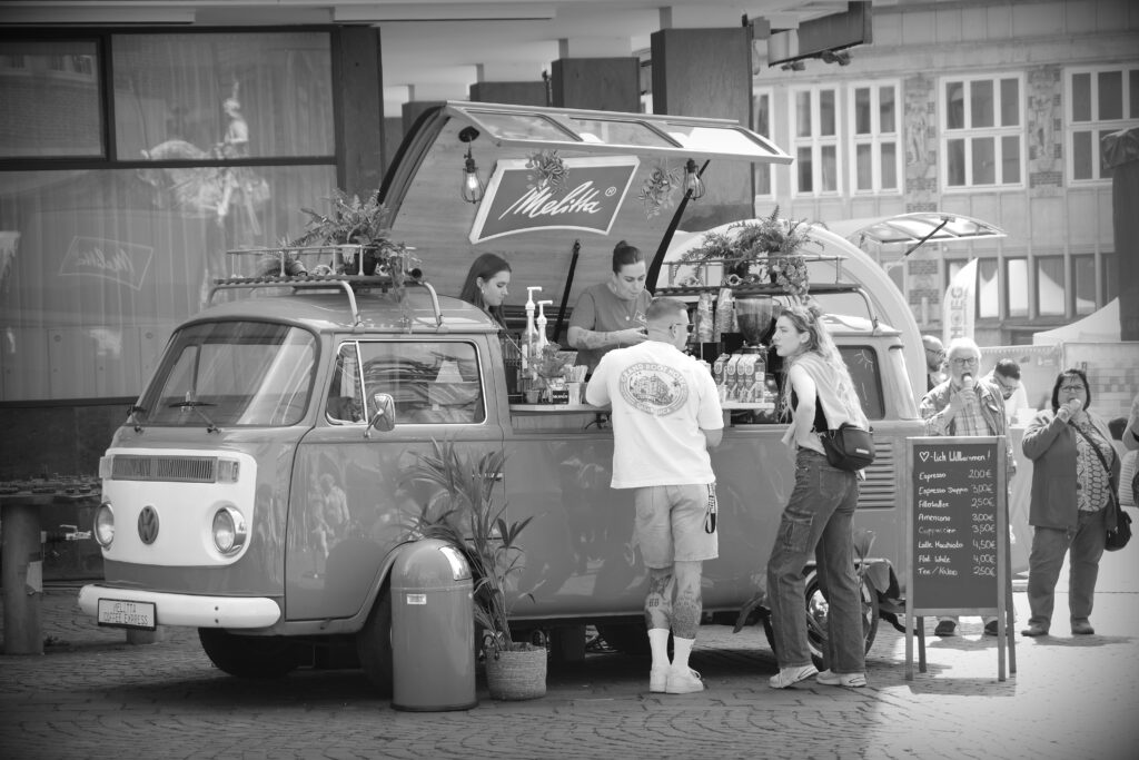 A coffee and drinks shop in a converted VW camper van, with a roof that opens upwards on one side. Bremen