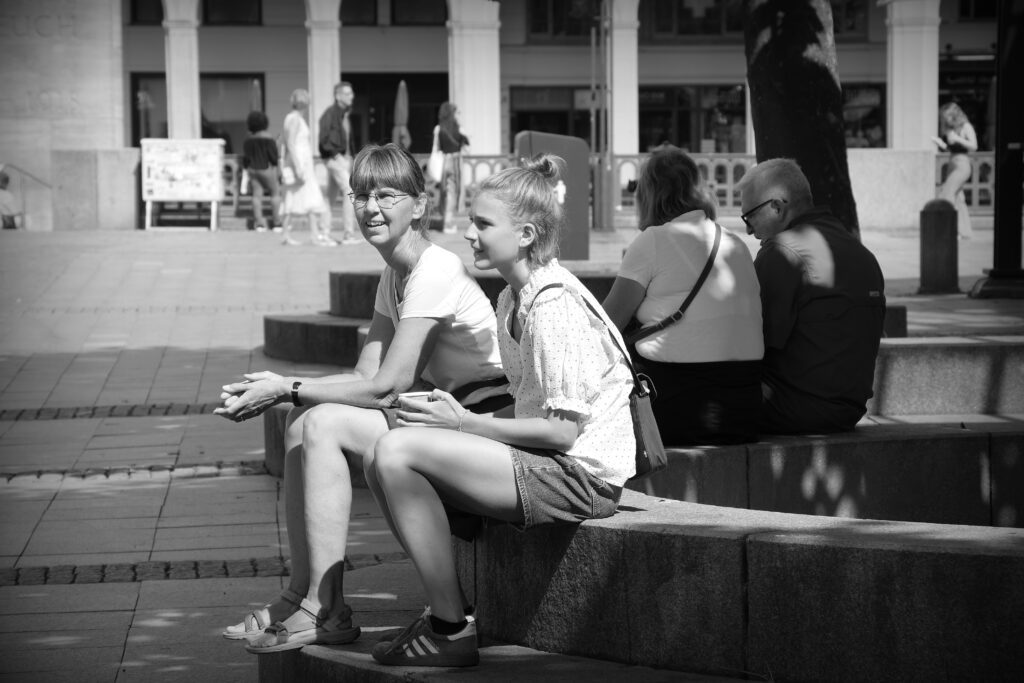 Two young women sitting together on the edge of a stone fountain in Hannover.