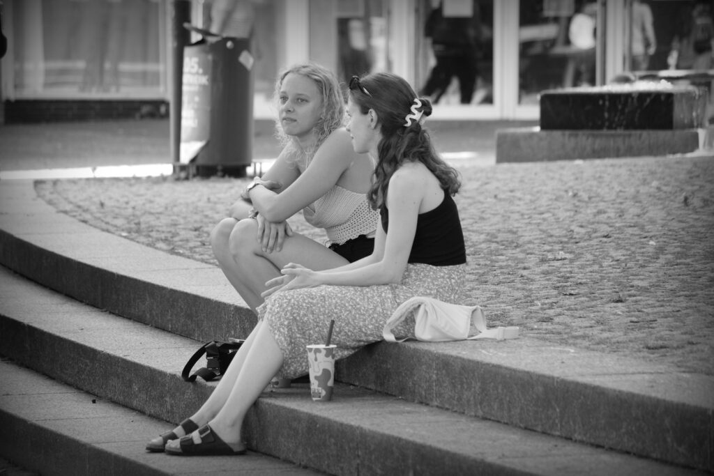 Two young women sitting together on stone steps in Hildesheim.