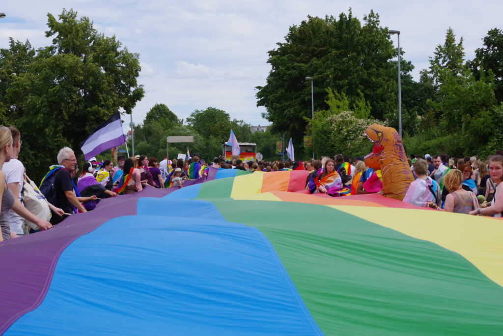 CSD in Schwerin, the march through and around the city, with the massive Pride flag carried by demonstrators along the route.