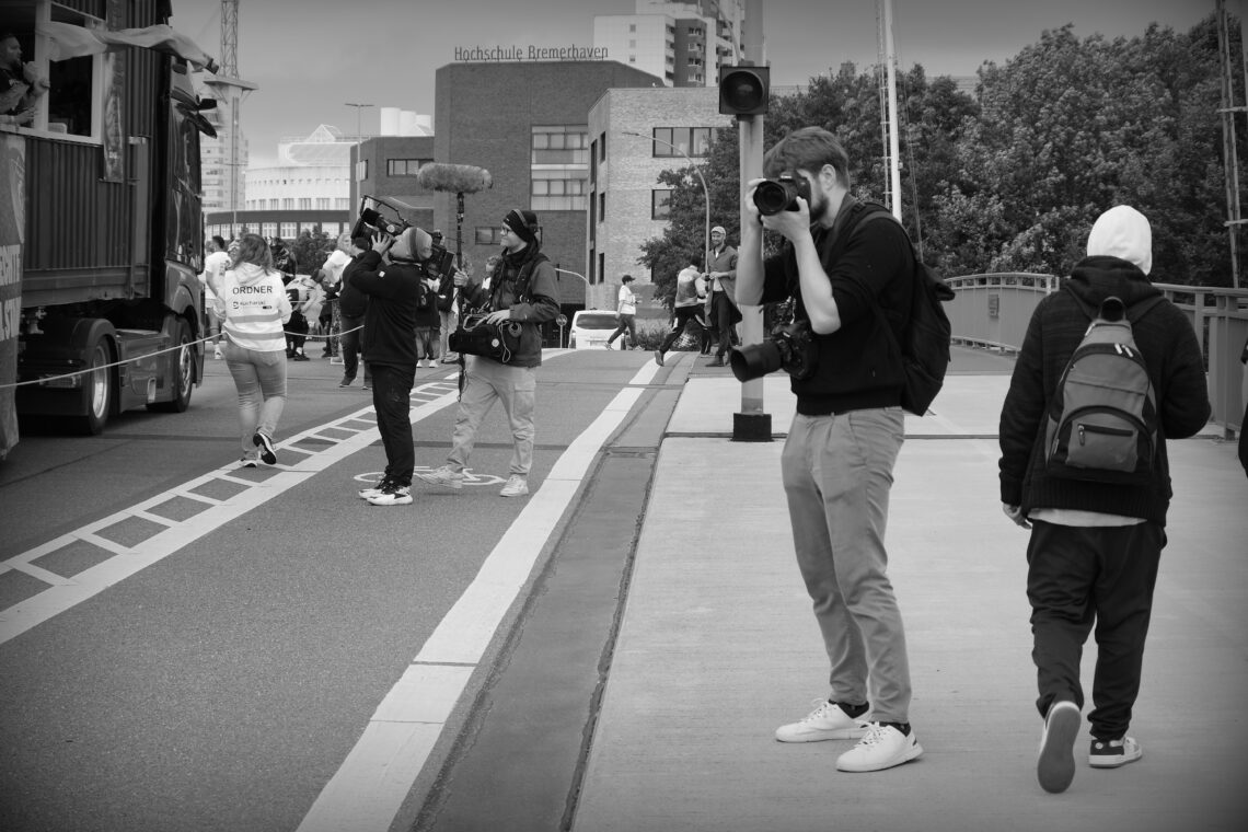 A photographer and a film crew working alongside the CSD Bremerhaven parade.