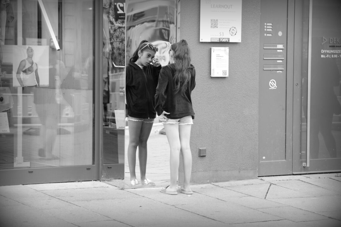 A young woman street singer taking a break to check herself in a mirror, in Osnabrück.