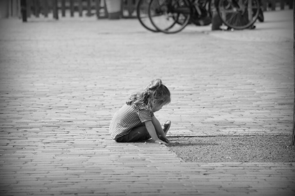 A small child playing in dirt around a tree in Schwerin.