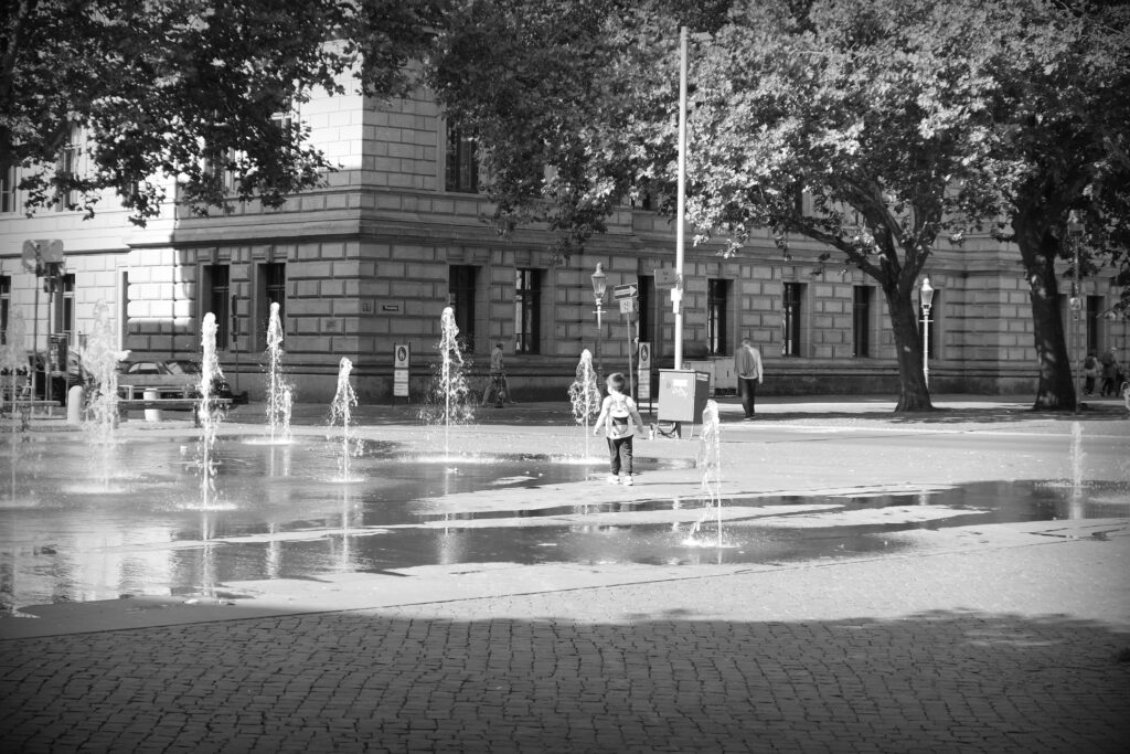 A small child running between the water fountains in Braunschweig.