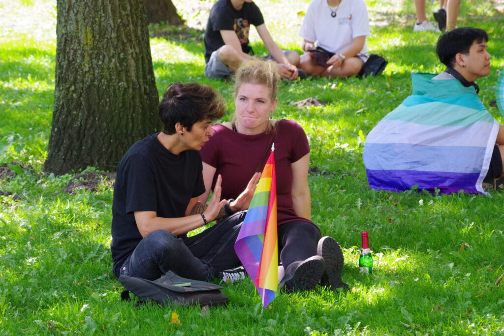 CSD Bremen: Two people sitting on the grass talking prior to the parade.