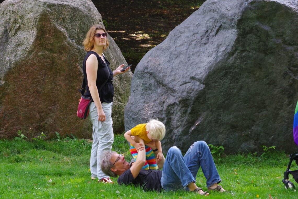 CSD Bremen: A small family, with one parent playing with a small child on the grass prior to the parade.