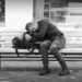 A possibly homeless person sleeping across his rucksack on a bench. Copyright Urban Camera 2024