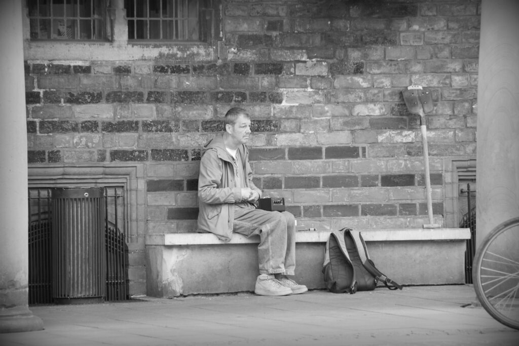 A homeless musician playing a self-made guitar - strings strung across the length of a common shovel - in Bremen. Copyright Urban Camera 2024