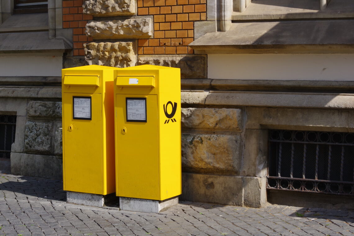 Two large yellow post boxes on a street outside an older brick building. Copyright Urban Camera.