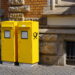 Two large yellow post boxes on a street outside an older brick building. Copyright Urban Camera.