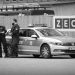 A monochrome photograph of a male and a female police officer standing in front of their vehicle by the wooden fencing of a building site in Bremen, Germany. Copyright Urban Camera.