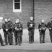 Monochrome photograph of a line of police officers in Bremen, Germany, attending an AfD publicity stunt, all dressed up with riot gear available. Copyright Urban Camera.